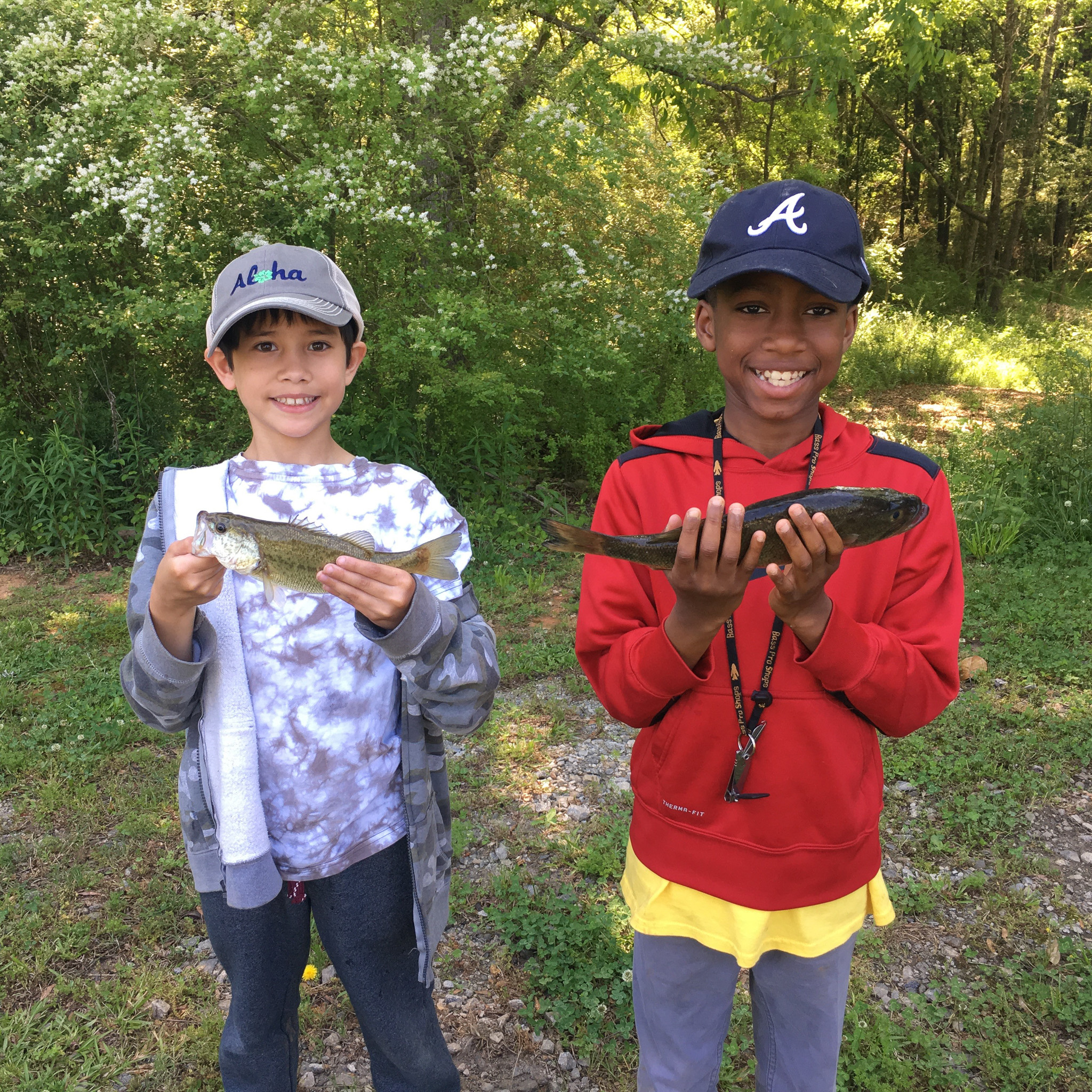 Two young boys hold up fish they caught.