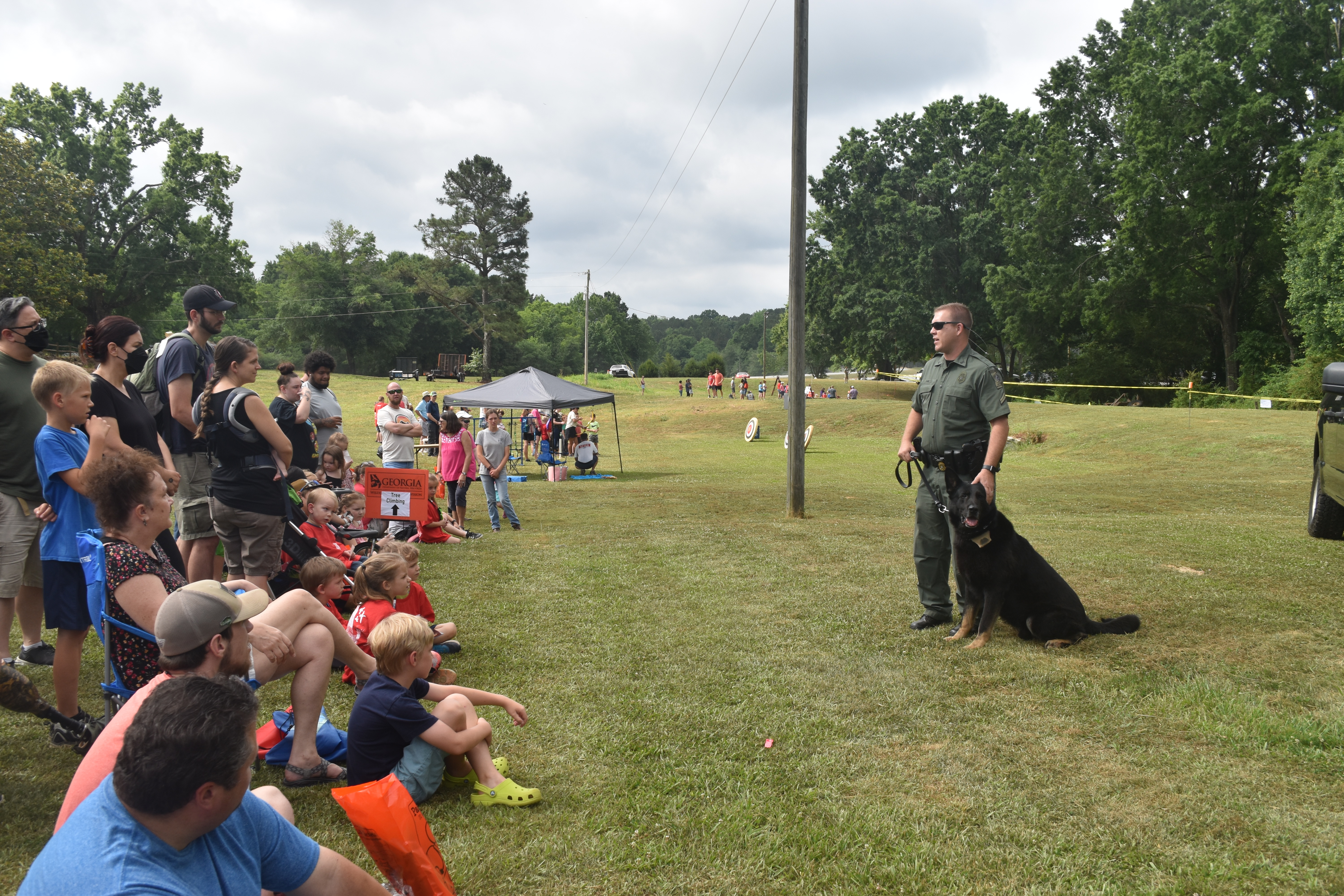 Children and parents gather around a field to watch K9-police unit demonstration