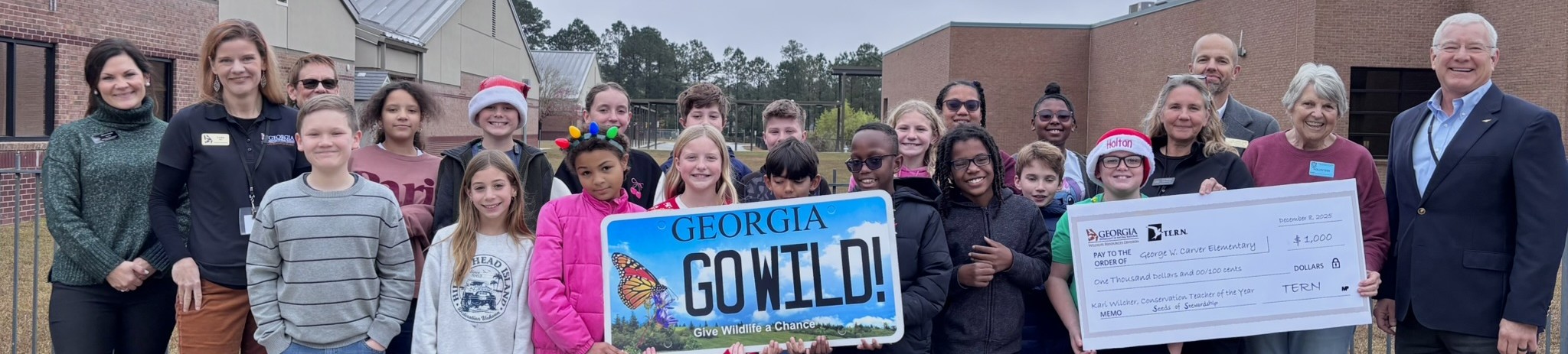 Carver elementary's 5th grade class hold a large check