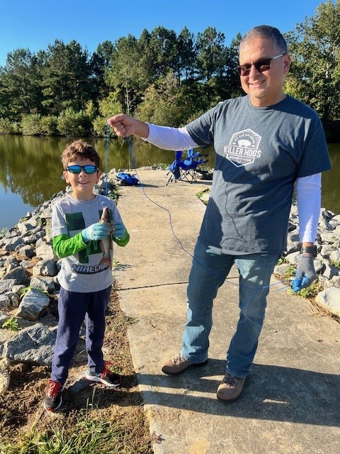 A young boy and his father hold up his first catch.